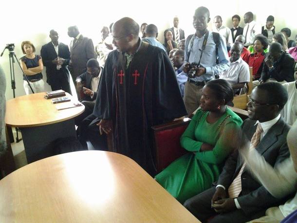 Plaintiff Frank Mugisha can be seen smiling after ruling announced, while Anti-Gay Martin Ssempa in robe looking on in dismay. 
